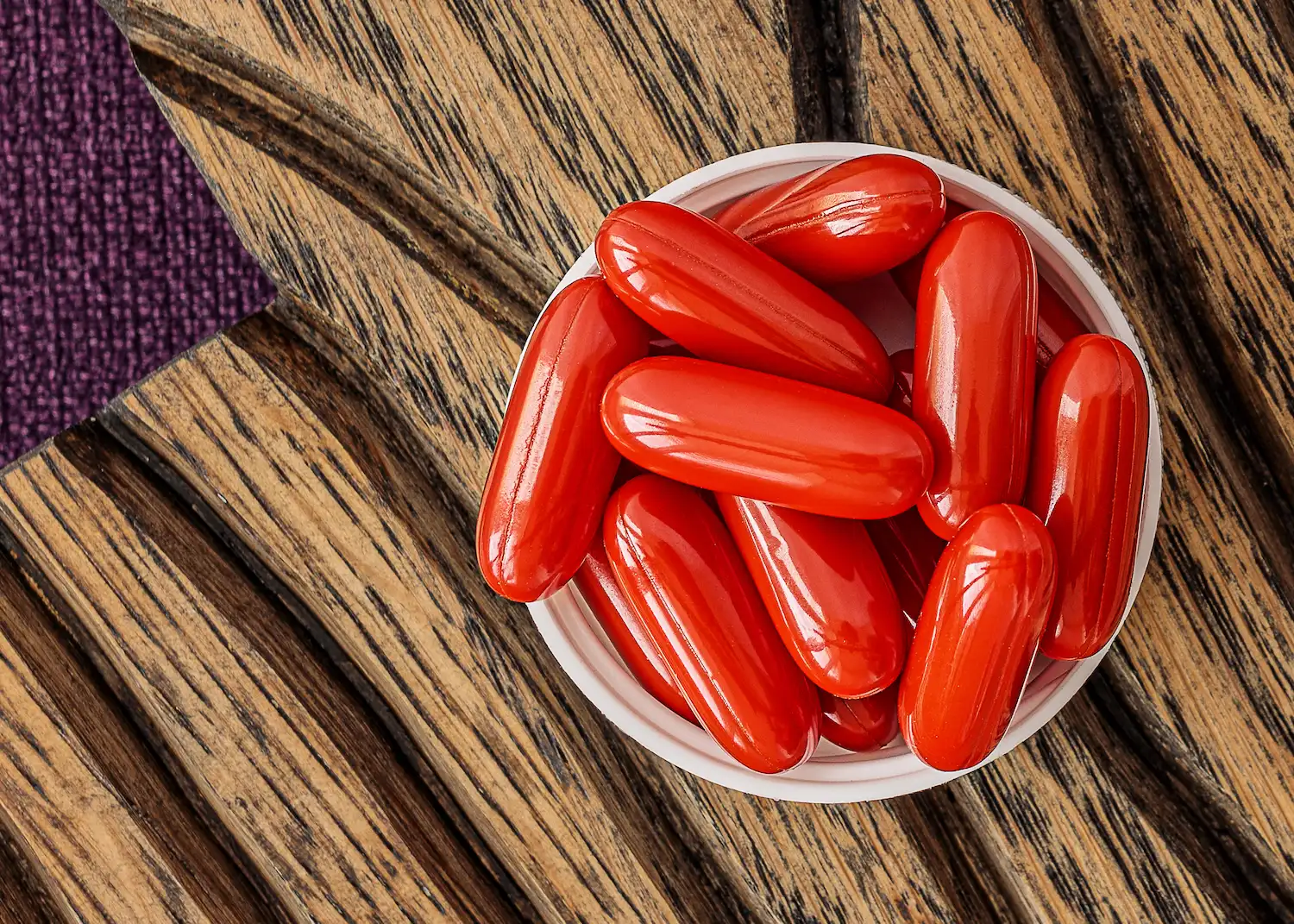 hands holding a white supplement tablet and a glass of water